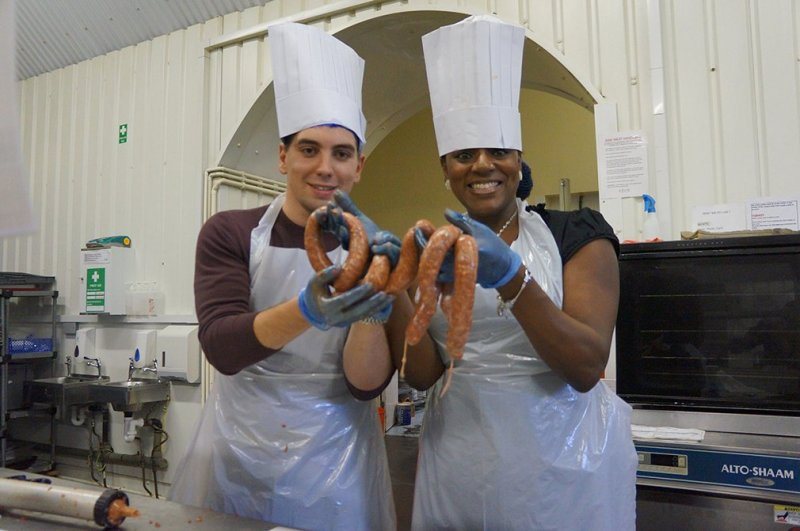 Účastníci soupeřivého teambuildingu Sausage Sensation od Catalyst se svými vyrobenými klobáskami