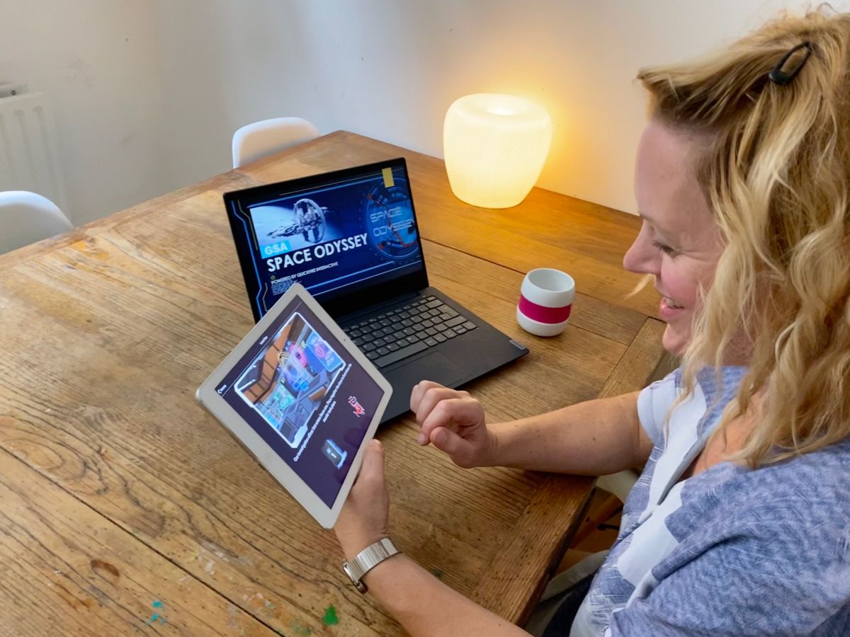 Woman laughs during Space Odyssey Online Teambuilding Game at Home with her Tablet